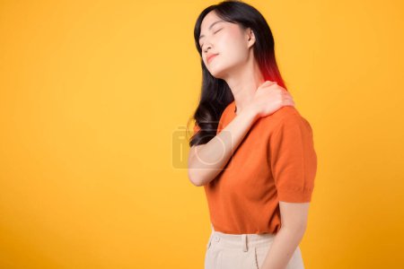 Foto de Dolor de cuello terapia concepto de síndrome de consultorio médico. joven asiático mujer 30s mujer persona usando naranja camisa celebración cuello músculo hombro dolor músculo lesión aislado en amarillo fondo. - Imagen libre de derechos