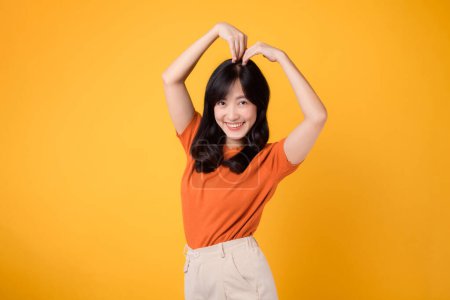 Photo for Experience the joyful embrace of love and positivity with a cheerful Asian woman 30s, wearing an orange shirt and beaming a heartwarming smile. - Royalty Free Image