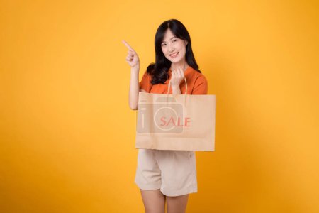 Photo for Radiate happiness and style while pointing to exciting deals. Young woman holding a bag, capturing shopping enthusiasm. - Royalty Free Image