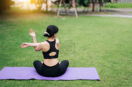 Téléchargez les photos : Portrait fit jeune femme asiatique en vêtements de sport rose avec tapis de yoga. étirement des muscles des bras dans le parc au coucher du soleil nature - en image libre de droit