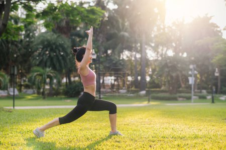Téléchargez les photos : Forme jeune femme asiatique trentaine en tenue de sport rose étire les muscles dans le parc avant de courir rafraîchissant. le concept de bien-être et d'un mode de vie sain en plein air avec une coureuse de fitness dans un parc public. - en image libre de droit