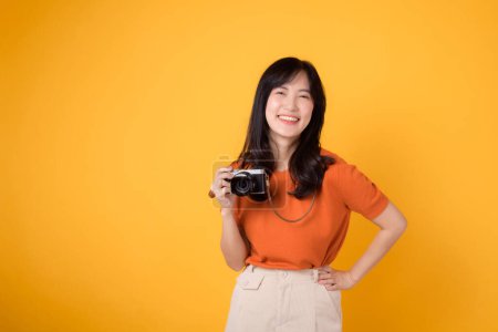 Téléchargez les photos : Jeune femme avec caméra isolée sur fond jaune capturant des souvenirs lors d'un voyage de vacances amusant. Concept aventure et photographie. - en image libre de droit