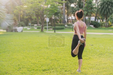 Photo for Female jogger, fit young Asian woman 30s in pink sportswear, warm up body in park before run. healthy outdoor lifestyle fitness runner girl against sunset. wellness and well-being concept. - Royalty Free Image