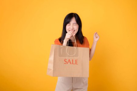 Photo for Fall in love with the surprise of the best deals while shopping! Trendy woman showcases joyful purchases isolated on yellow background, reflecting the excitement of savvy shopping. - Royalty Free Image