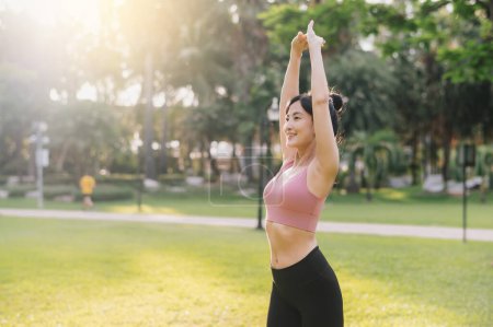 Foto de Bienestar y estilo de vida saludable retrato de mujer asiática de 30 años en ropa deportiva rosa. preparar y estirar los músculos del brazo antes de la puesta del sol correr en el parque. fitness exterior y abrazar una vida equilibrada. - Imagen libre de derechos