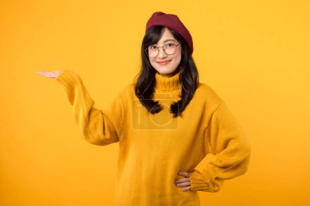 Mujer asiática linda 30s con camisa amarilla que apunta al espacio de copia. P