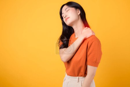 Téléchargez les photos : Jeune femme asiatique 30s femme portant chemise orange tenant cou douleur musculaire épaule blessure musculaire isolé sur fond jaune.Cou douleur thérapie bureau médical concept de syndrome. - en image libre de droit