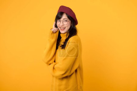 Téléchargez les photos : Portrait jeune asiatique femme heureux sourire portant pull jaune et béret rouge montrant penser langage du corps isolé sur fond jaune. - en image libre de droit