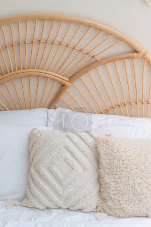 Téléchargez les photos : Image détaillée d'une chambre avec tête de lit en bois brun tissé avec mur blanc et oreiller blanc et brun. - en image libre de droit