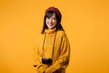 Una artista creativa, esta joven asiática, vestida con suéter amarillo y boina roja, captura momentos con su cámara, un pasatiempo encantador.