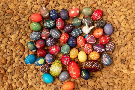 muchos huevos de Pascua coloridos pintados a mano, de acuerdo con la tradición sorbia en la superficie del mástil de rafia tejido, cesta tejida soleada, espacio de copia
