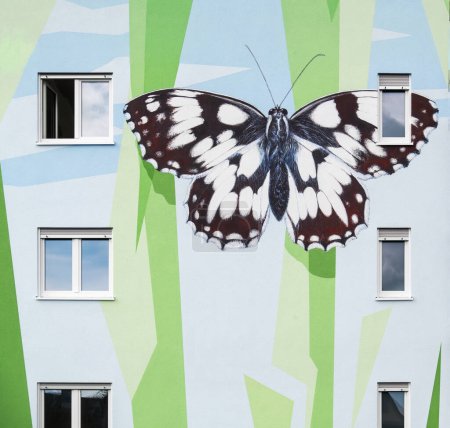 Foto de Detalle de la casa de un bloque de apartamentos moderno, diseñado artísticamente con un patrón mural de formas poligonales que simboliza elementos florales abstractos y una mariposa a cuadros pintada, Langen, Alemania - Imagen libre de derechos