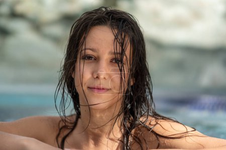 portrait of a sexy happy smiling brunette wet woman sensually seductive at the spa wellness pool, copy space