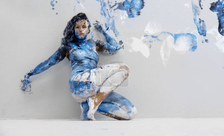 joven morena sexy Mujer en ropa interior, ropa deportiva, artísticamente abstracta pintada con pintura blanca, negra y azul, sentada en el suelo en el estudio de artistas, espacio para copiar