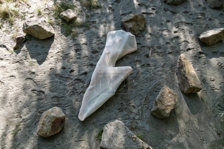 Téléchargez les photos : Sexy femme nue en coton blanc transparent robe de bas de cocon couché entre les pierres sur la plage du Danube, en plein air dans la nature, espace de copie - en image libre de droit