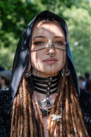 Young, smiling, female goth woman portrait with piercings and metal jewelry on her face with black cap and dreadlocks, on the annual WGT in Leipzig, victorian picnic, Clara-Zetkin-Park, copy space,