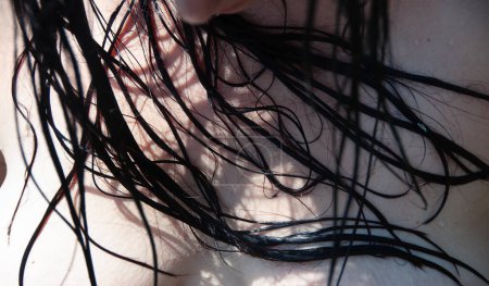 Oberkörper und Busen einer Frau mit nassen lockigen schwarzen Haaren, die an ihnen kleben, sinnlich schönes Porträt einer naturliebenden Frau mit nassen brünetten Haaren am sonnigen Badesee, Kopierraum