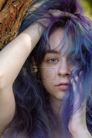 Retrato de una sensual chica emo sexy con el pelo violeta púrpura jugando seductoramente con su cabello