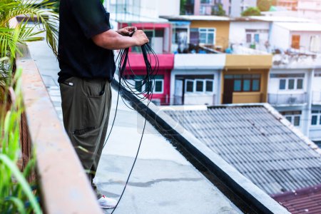 Technicians are installing fiber optic cables for internet on the rooftop. Work on wiring fiber optic cables for customers in their homes.