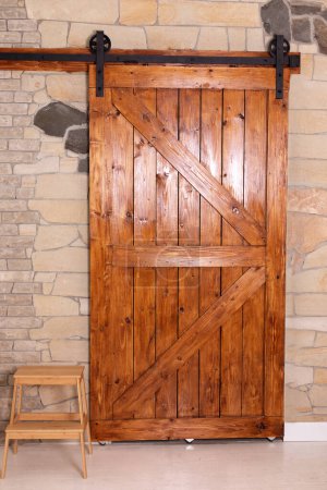 Foto de Sliding barn wooden door in indoors. Sliding old Barn Door in modern room. Rustic farm wood sliding barn style door at home. - Imagen libre de derechos