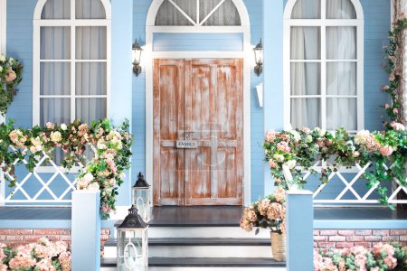 House entrance staircase at home decorated for easter. Wooden porch of house with different flowers. Terrace of summer house. Spring design home with bloom flowers and decoration lanterns on steps. 