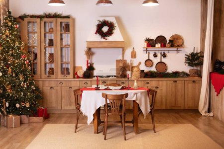 Innenarchitektur skandinavische Holzküche mit Möbeln. Ukrainische Küche im rustikalen Stil mit rundem Tisch und Stühlen. Korbflechter Didukh, Kerzen und Brot auf dem gedeckten Festtisch zu Weihnachten. 
