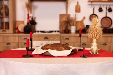 Wicker-Didukh. Hergestellt aus Stroh verschiedener Getreidesorten. Ukrainische Weihnachtsdekoration aus Stacheln. Ukrainische Traditionen, Kerzen und Brot auf dem Tisch zu Weihnachten. Ukrainischen Stil Interieur Küche mit Dekor 