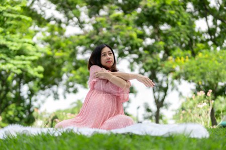 Foto de Retrato de mujer embarazada asiática relajándose haciendo yoga en el parque - Imagen libre de derechos