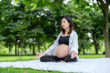 Foto de Retrato de mujer embarazada asiática relajándose meditando en parque - Imagen libre de derechos