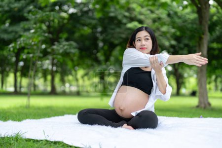 Foto de Retrato de mujer embarazada asiática relajándose haciendo ejercicio en el parque - Imagen libre de derechos