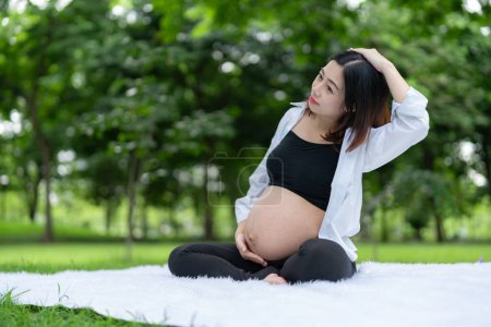 Foto de Retrato de mujer embarazada asiática relajándose haciendo ejercicio en el parque - Imagen libre de derechos