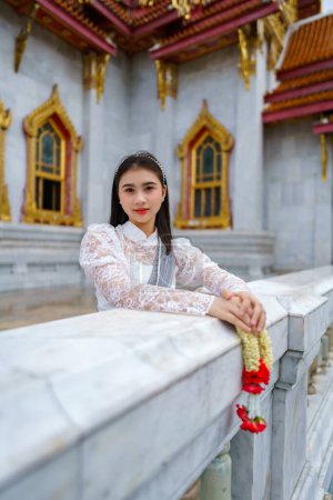 Foto de Retrato de una hermosa mujer joven con traje nacional tailandés Rattanakosin en un templo construido de acuerdo con el arte tailandés en Tailandia - Imagen libre de derechos