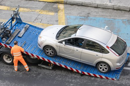 Téléchargez les photos : Galice, Espagne ; 08 juillet 2023 : Un travailleur d'assistance routière soulève une voiture sur une dépanneuse. Service de remorquage sur la ville - en image libre de droit