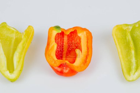 Foto de Halved green and red bell peppers isolated on white background. Cutting contour. View from above - Imagen libre de derechos