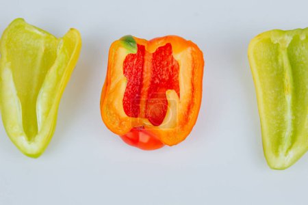 Foto de Halved green and red bell peppers isolated on white background. Cutting contour. View from above - Imagen libre de derechos