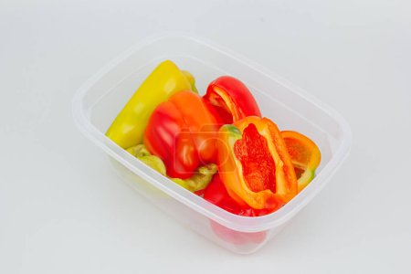 Foto de Mixed organic red, green and yellow peppers in a container. Storage of vegetables. Organization of space in the kitchen - Imagen libre de derechos