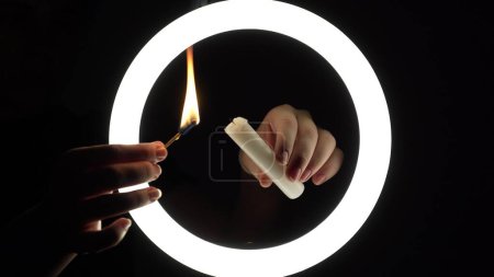 Téléchargez les photos : Female hands light a candle close-up on a black background. burning fire on a candle stick. The concept of ritual actions. - en image libre de droit
