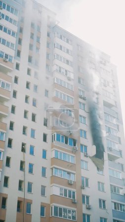 Foto de KYIV, UKRAINE - NOVEMBER 15, 2022: fire in an apartment building. Blue smoke billows from the windows of the apartment. Extinguishing a fire in an apartment building. vertical video - Imagen libre de derechos