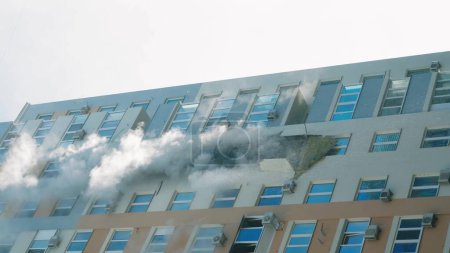 Foto de KYIV, UKRAINE - NOVEMBER 15, 2022: Fire in the apartment. Thick gray smoke comes from the windows of an apartment building. Extinguishing a fire in an apartment building. vertical video - Imagen libre de derechos