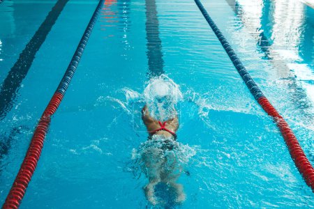Téléchargez les photos : Nageuse couronnée de succès nageant dans la piscine. Un athlète professionnel est déterminé à remporter le championnat - en image libre de droit