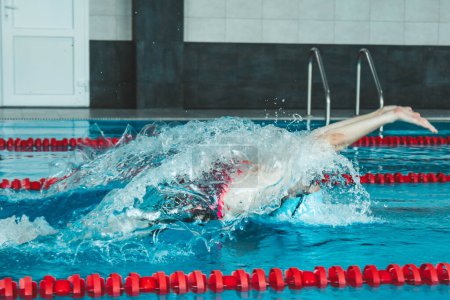 Foto de Hermosa nadadora femenina usando bypass frontal, estilo libre en la piscina. Preparación de atletas profesionales para ganar el campeonato - Imagen libre de derechos
