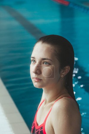 Foto de Joven chica morena hermosa en el fondo de la piscina. Retrato de una chica cerca de la piscina. Natación, estilo de vida saludable - Imagen libre de derechos