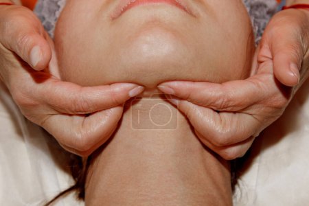 Téléchargez les photos : Spécialiste du spa fait massage du visage à une jeune fille dans une casquette médicale. soins de beauté close-up
. - en image libre de droit
