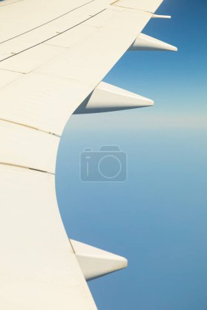 Téléchargez les photos : View of the wing of an airplane, traveling on an international flight, at high altitude, with a blue sky and no clouds - en image libre de droit