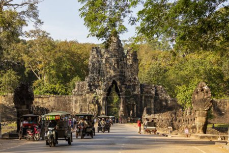 Téléchargez les photos : Angkor, Cambodge - Nov, 2019 : Trafic de véhicules et tuk tuk, passant par la porte sud qui donne accès au temple Bayon, dans l'ancienne ville d'Angkor, Cambodge - en image libre de droit