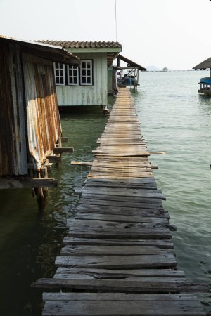 Photo for A wooden jetty crosses next to humble fishermen's houses, in the southern part of the island of Koh Chang, Gulf of Thailand - Royalty Free Image