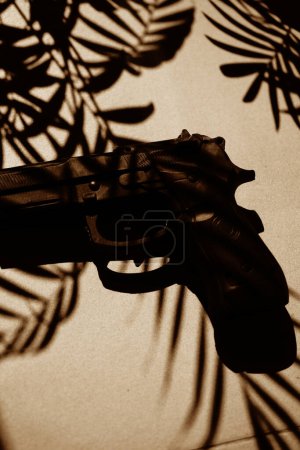 Foto de Espía thriller libro cubierta diseño pistola gun.on piso con sombras de palmeras tropicales - Imagen libre de derechos