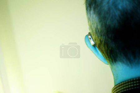 Téléchargez les photos : Vieil homme blanc caucasien portant une aide auditive numérique moderne dans l'oreille avec des cheveux gris. - en image libre de droit
