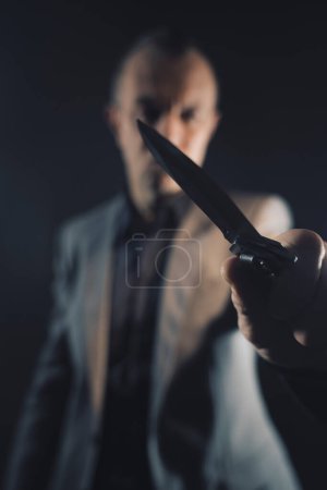 Foto de Asesino asesino asesino sosteniendo cuchillo arma de hoja en oscuro espeluznante foto libro cubierta diseño. - Imagen libre de derechos