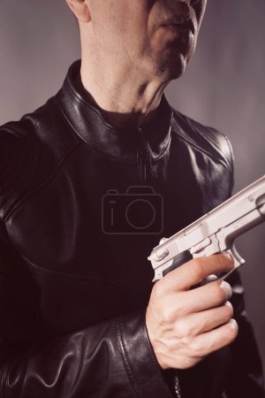 Foto de Chaqueta de cuero negro asesino detective asesino asesino asesino con pistola retrato foto. - Imagen libre de derechos